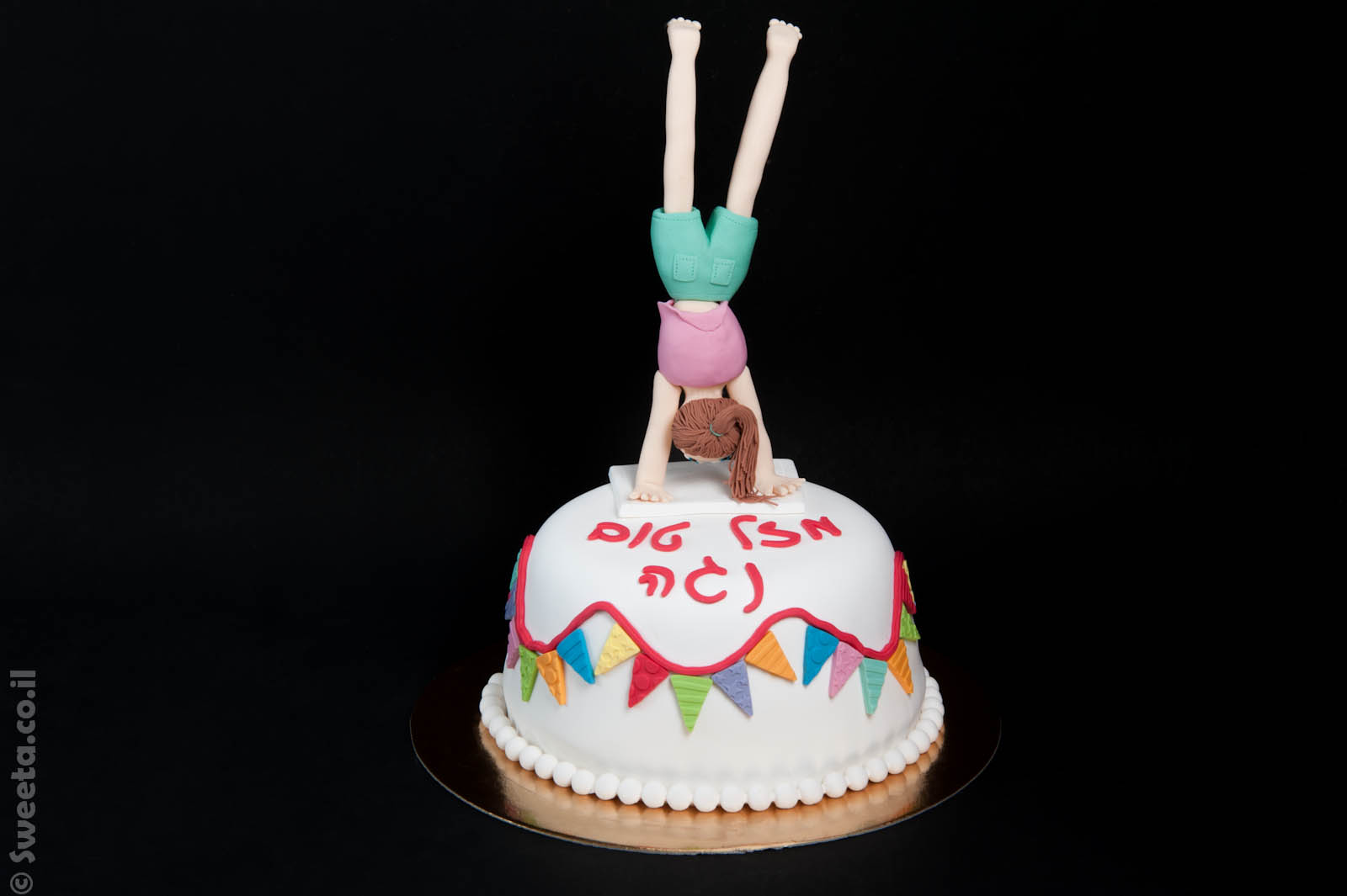 עוגה מבצק סוכר ליום הולדת עם דמות של מתעמלת בתרגיל עמידת ידיים