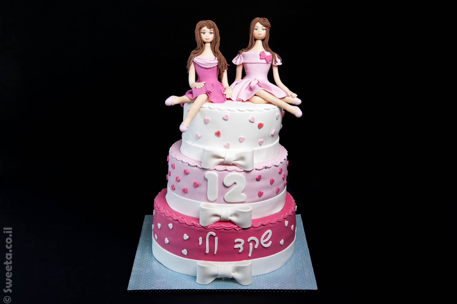 עוגת בת מצווה שלוש קומות של שקד ולי עם שתי דמויות יושבות מפוסלות בבצק סוכר